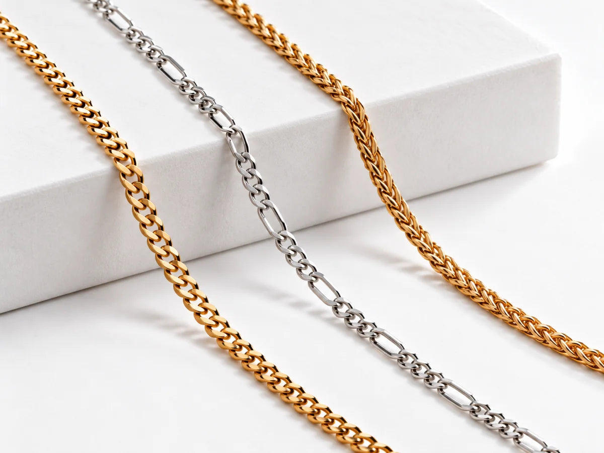 Gold Cuban and Wheat chains with a silver Figaro chain on a white studio display.